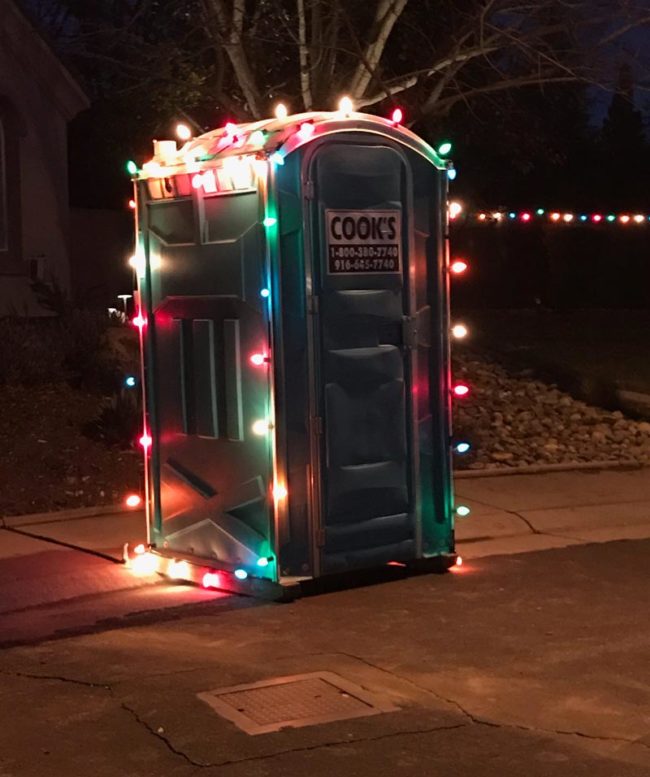 Un baño químico para el patio decorado con luces navideñas de colores es Navidad para todos